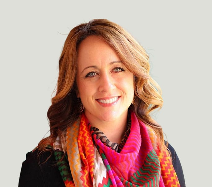 A smiling woman wearing a colorful scarf.