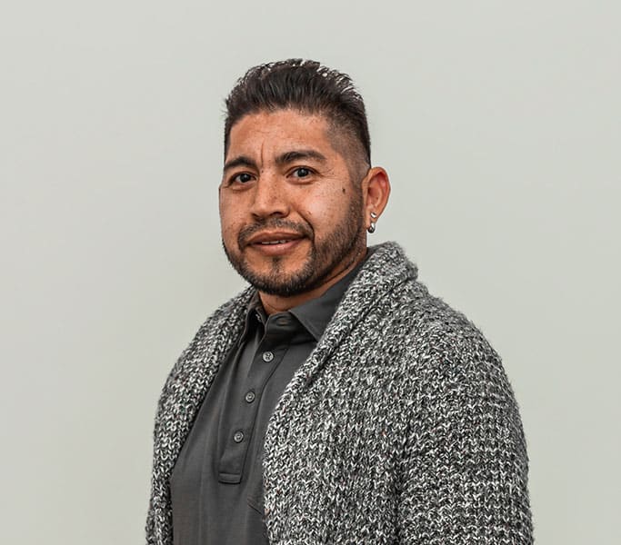 A man wearing a grey cardigan and black shirt.