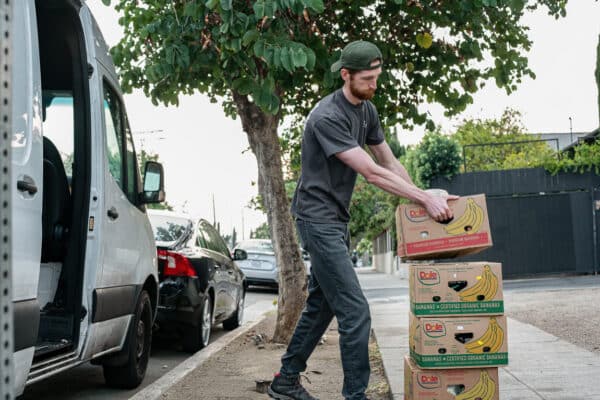 A man stacking boxes in front of a van.