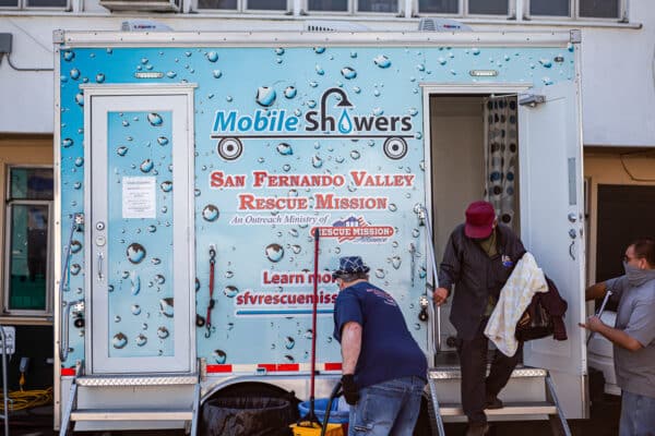 Two men standing next to a mobile shower trailer.